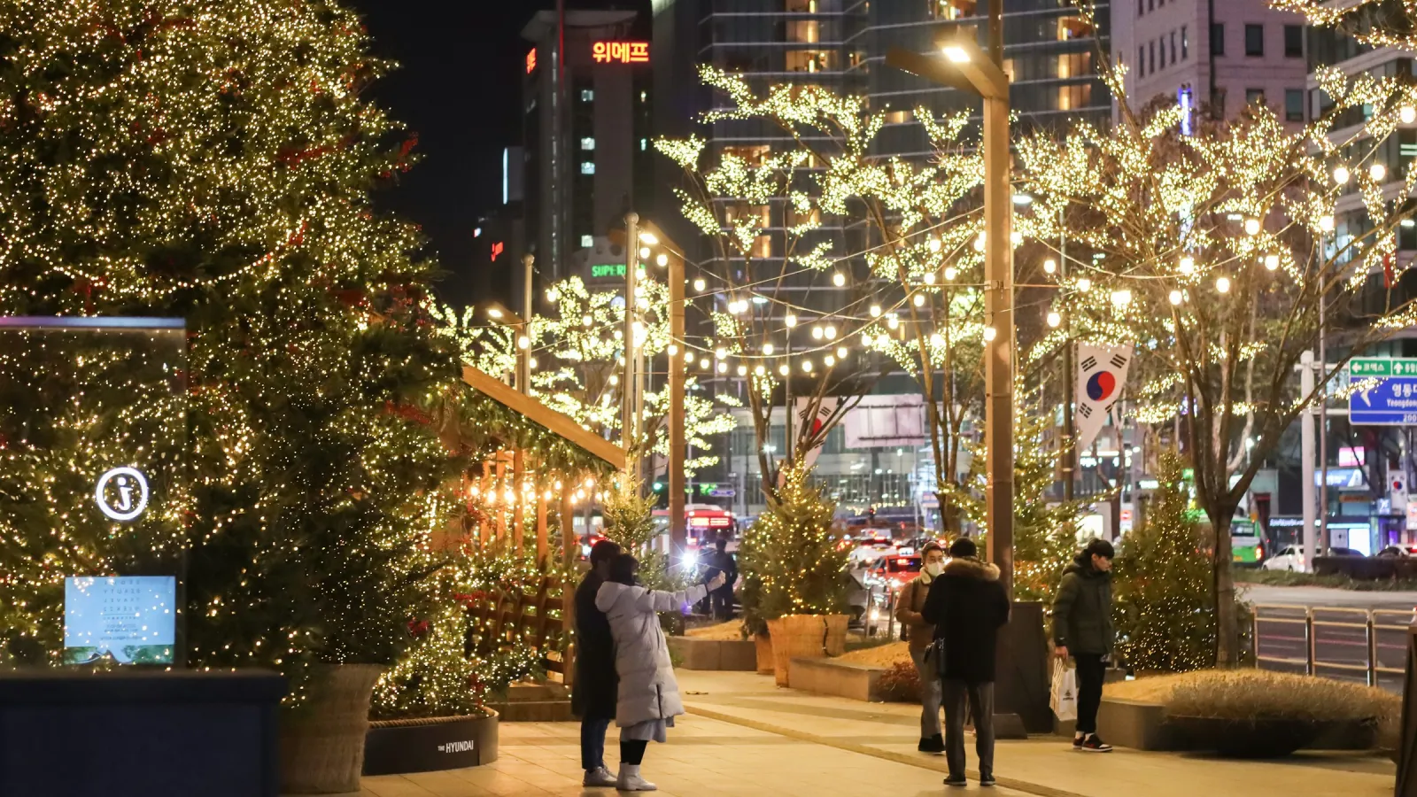A street by Yeongdong-daero, Seoul, in December 2022: a big Christmas tree, trees wrapped in lights, and people stopping for photos.